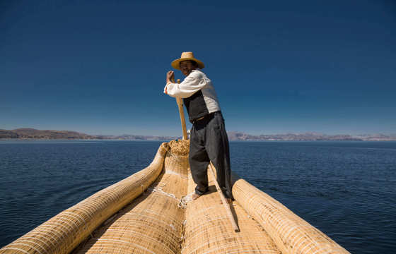 Traditional reed boat glides across Peru's Lake Titicaca in the Andean highlands.
