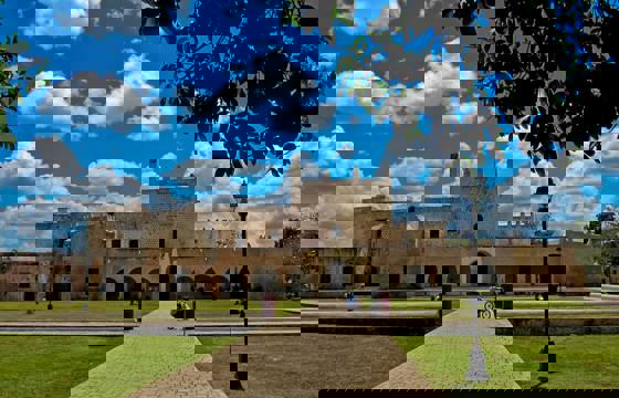 Colonial-era Convento de San Bernardino in Valladolid, Yucatan, framed by a bright sky and well-kept gardens.