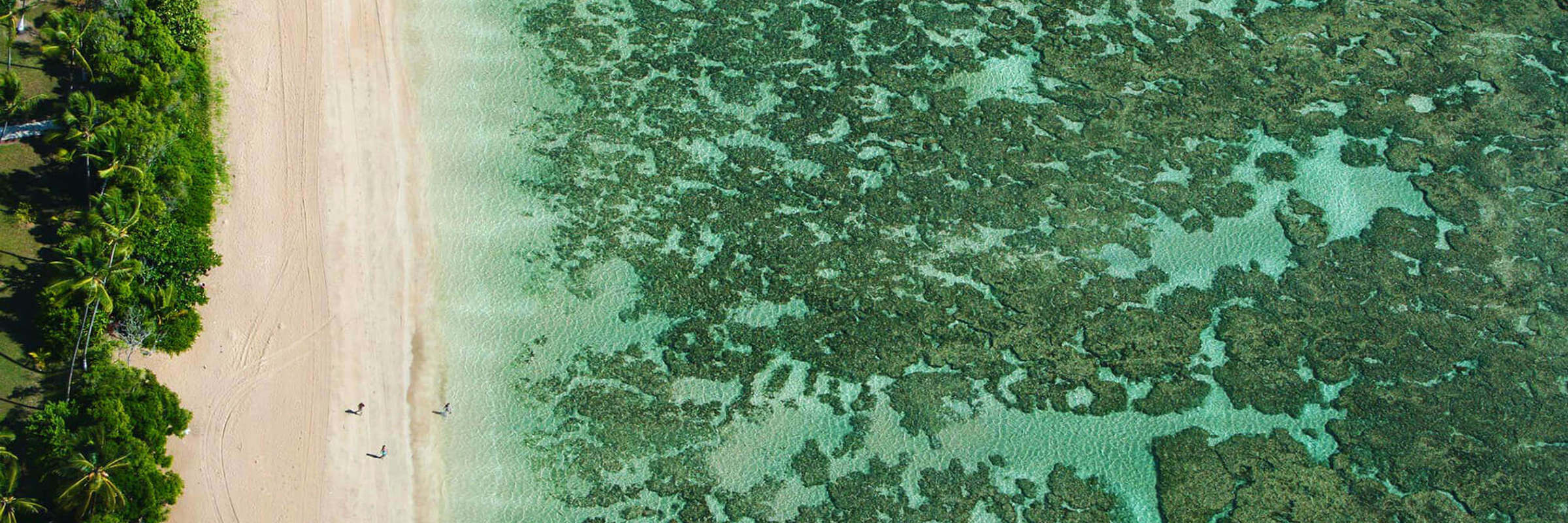 Aerial view of the turquoise sea, coral reef, and tropical shoreline at Morro de Sao Paulo, Bahia, Brazil. 