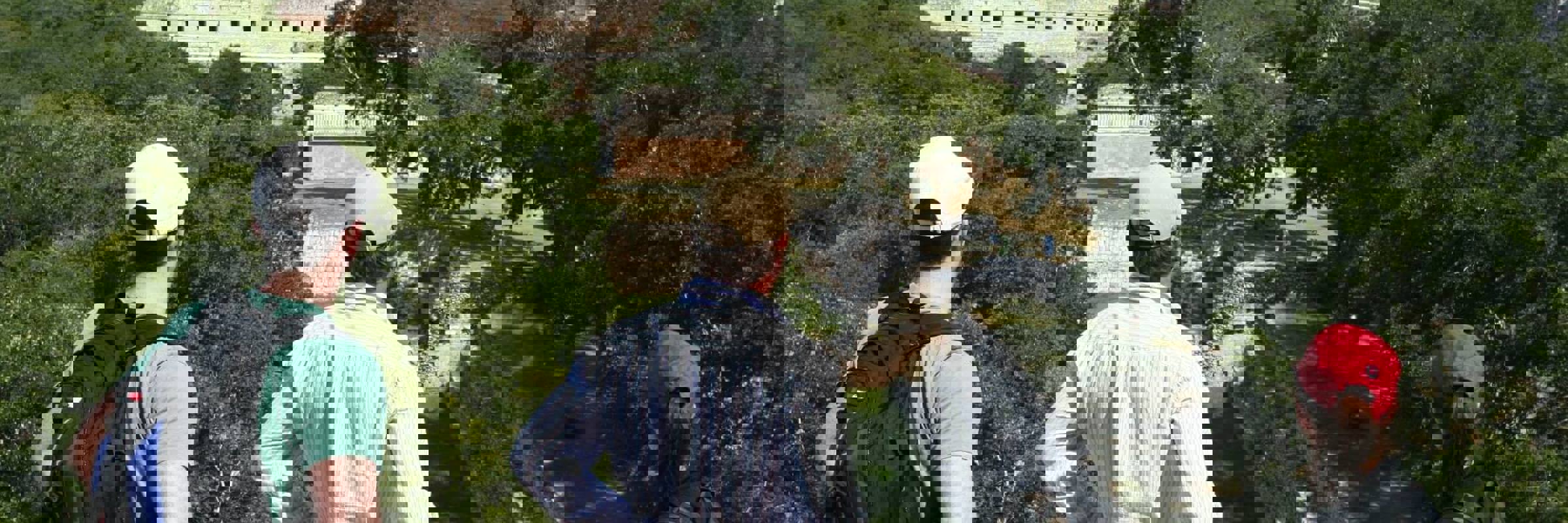 Tourists enjoying a panoramic view of the ancient Mayan ruins at Uxmal, Yucatan, Mexico, surrounded by dense green jungle.