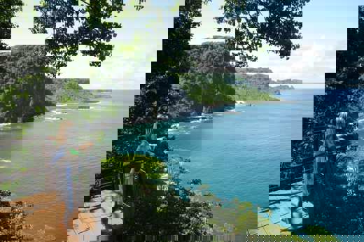 Woman at a cliffside viewpoint overlooking the rugged coastline and turquoise waters of Fernando de Noronha. 