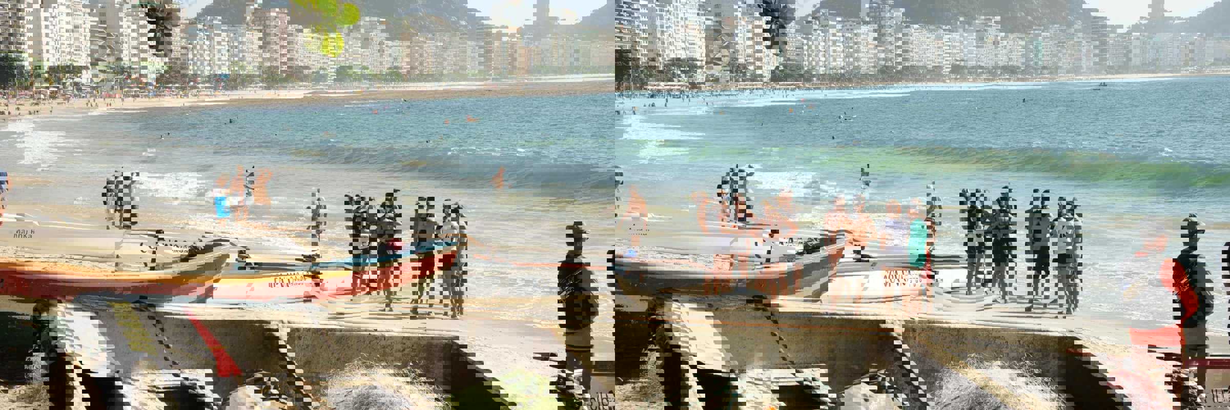 Traditional fishing boats and nets on Copacabana Beach with the Rio de Janeiro skyline and mountains in the background. 