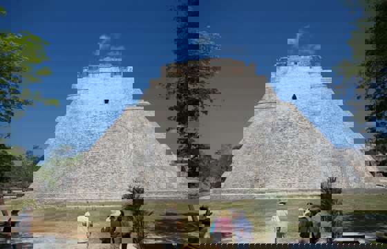 The Pyramid of the Magician at Uxmal, Yucatan, Mexico, a towering Mayan structure with steep sides and tourists at the base.