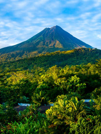 Arenal Volcano rises above the tropical forest of Costa Rica, framed by colorful lodges.