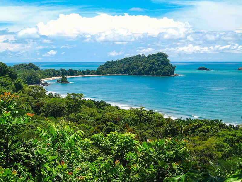 Tropical coastal view from Manuel Antonio National Park, with forested hills and turquoise Pacific waters. 