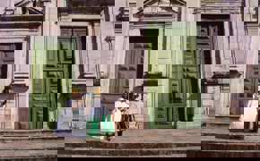 Women in traditional Baiana dresses standing outside historic green doors in Salvador's Pelourinho district, Bahia, Brazil.